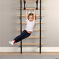 Young child wearing white t-shirt and navy leggings hanging from wooden ladder bars mounted on wall