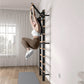 Woman wearing white sports bra and tan leggings using black wall-mounted ladder bars with wooden rungs in bright home gym