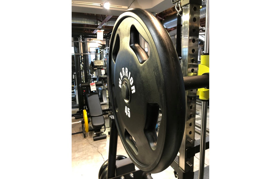 Black rubber Olympic weight plate with grip handles, marked 45 pounds, displayed in gym setting