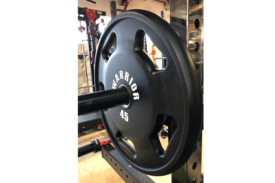 Black Warrior 45-pound urethane Olympic weight plate with grip handles, on barbell in gym setting