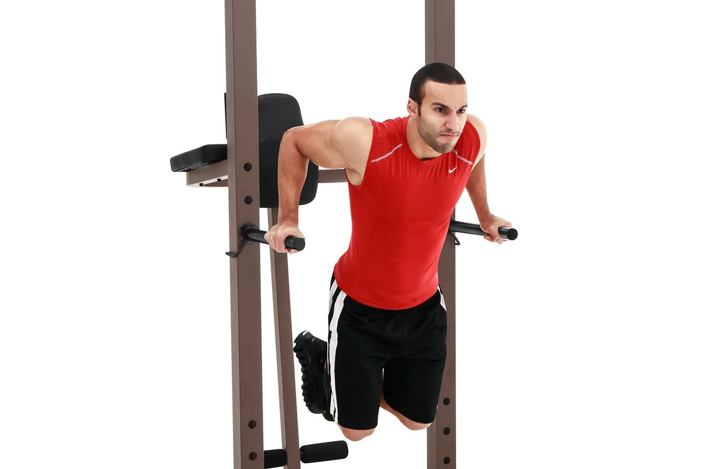 Man wearing red sleeveless shirt performing dip exercise on brown metal power tower with black padding and handles