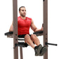 Man wearing red sleeveless athletic shirt and black shorts with white stripes using Warrior VKR/Dip Power Tower with taupe fr