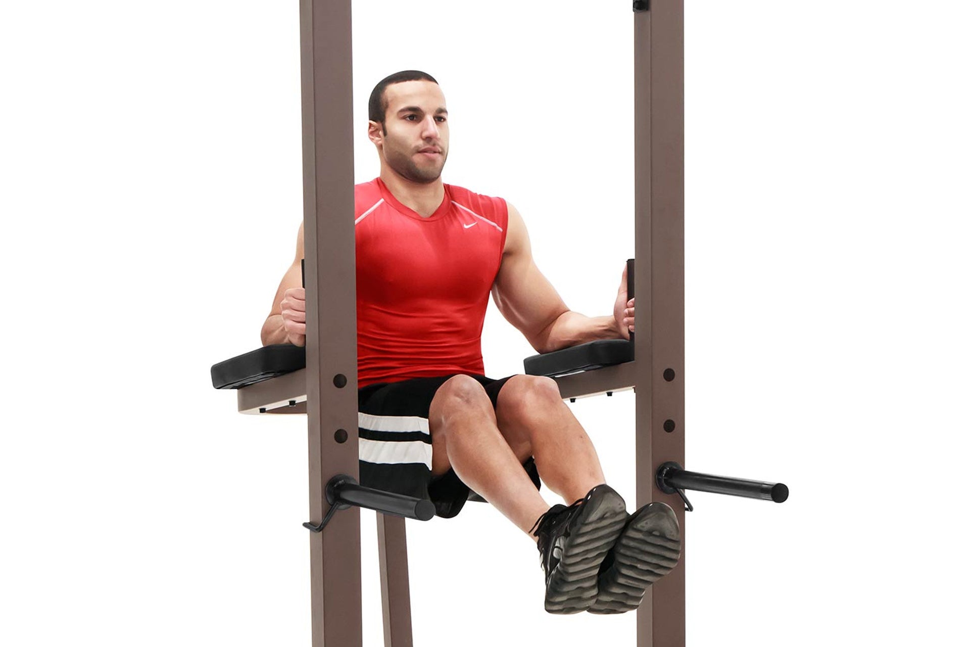Man wearing red sleeveless athletic shirt and black shorts with white stripes using Warrior VKR/Dip Power Tower with taupe fr