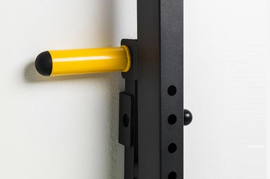 Yellow and black wall-mounted squat rack pull-up bar with black metal frame mounted on white wall