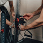 Two people assembling black and red cable pulley system mounted on wall, showing dual stack weights and carabiners