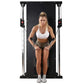 Woman using black and silver cable pulley home gym system with dual weight stacks, wearing white sports bra and olive shorts