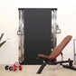 Warrior Wall Mounted Cable Pulley Home Gym System with two weight stacks, brown adjustable weight bench, and dumbbells on woo