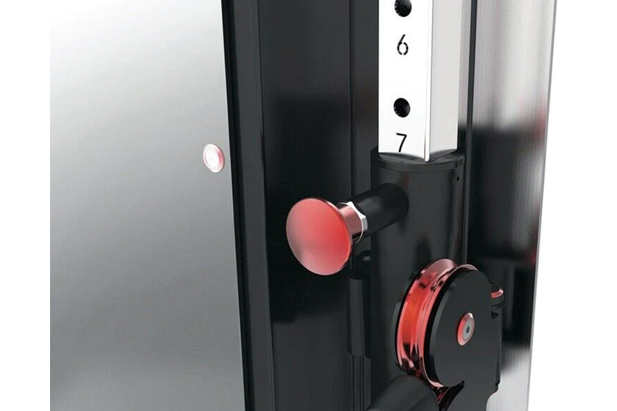 Warrior wall-mounted cable pulley home gym system with two red and black weight stacks, adjustment lever, and numbered scale 