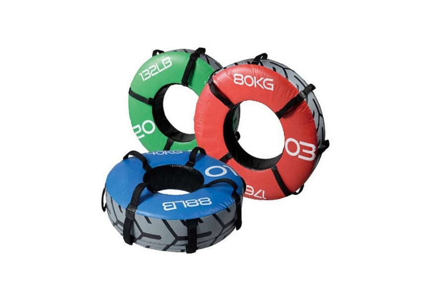 Three colored weighted training tires in green, red, and blue with black handles, displaying weight markings on white backgro