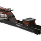 WaterRower Club rowing machine with dark wood frame, black base, water tank, and padded seat on white background
