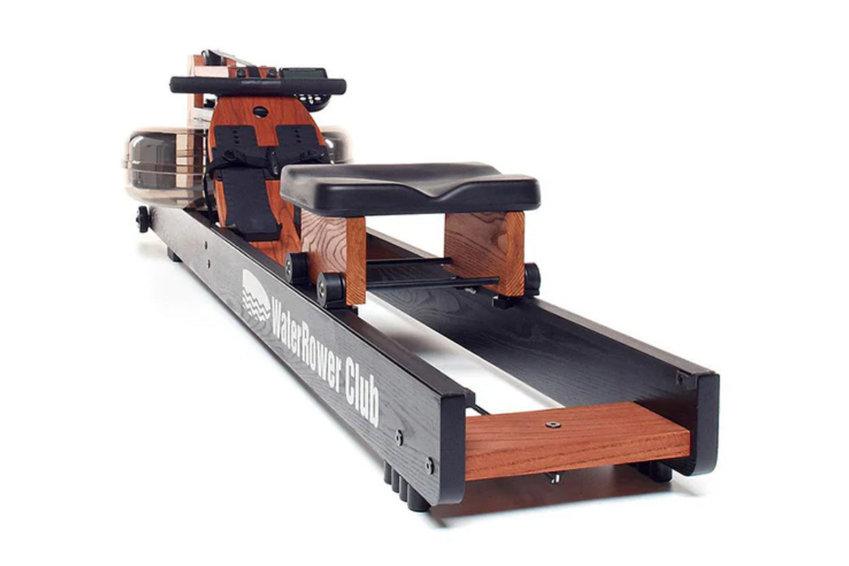 WaterRower Club rowing machine with orange wood frame, black rail, and water resistance tank on white background