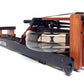 WaterRower Club rowing machine with orange wood frame, black base, and water tank resistance chamber on white background