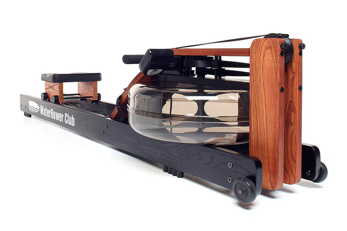 WaterRower Club rowing machine with orange wood frame, black base, and water tank resistance chamber on white background