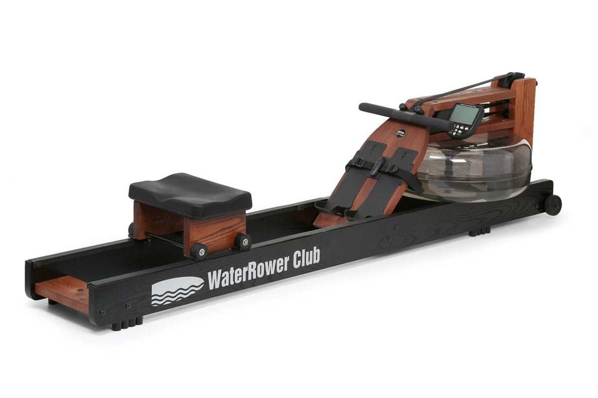 WaterRower Club rowing machine with wooden frame, black footrest, digital display monitor, and water resistance tank on white