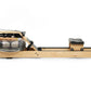 WaterRower oak rowing machine with water resistance tank, black foot pedals, and seat on white background