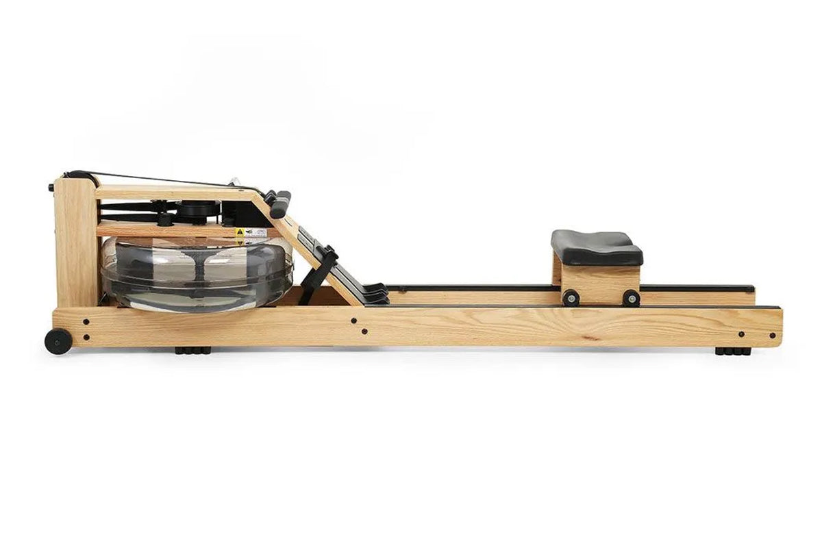 WaterRower oak rowing machine with water resistance tank, black foot pedals, and seat on white background