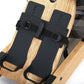 Black foot pedals with nylon straps and metal buckles on natural oak rowing machine footplate, flat lay view