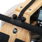 Water rowing machine with natural oak wood frame, black magnetic resistance unit, and digital performance monitor displaying 