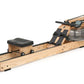 Wooden rowing machine with natural oak frame, black seat, footrest straps, and digital monitor on white background