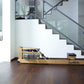 Natural wood rowing machine with glass monitor and black accents on dark wood floor, shown in modern home interior with stair