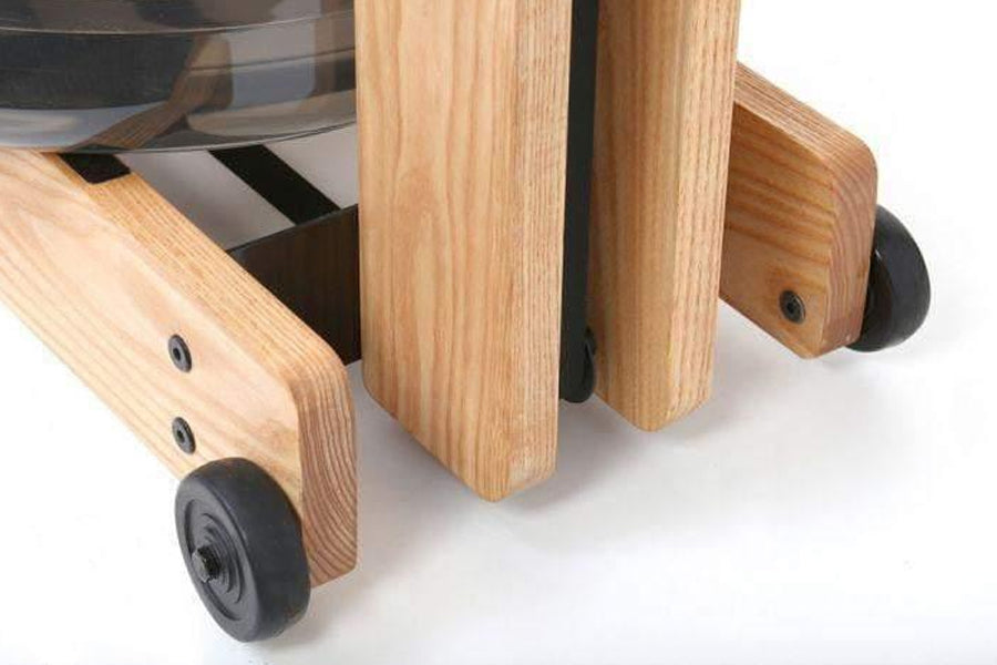 Natural wood rowing machine with black wheels and metal hardware, detail of wooden leg and caster wheel on white background