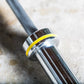 York Women's Elite Competition Olympic Bar with silver finish and yellow stripe band on concrete surface